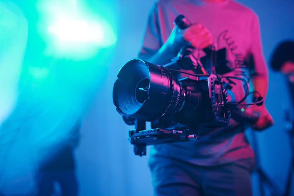 Close-up Of Young Cameraman Shooting With Professional Camera